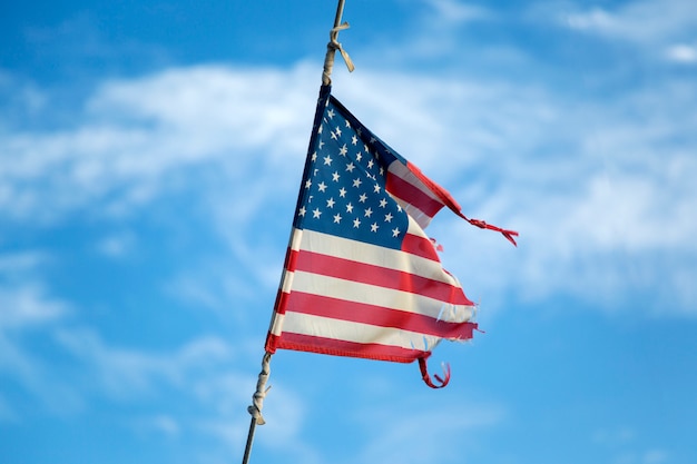 bandera americana rota ondeando en el mástil