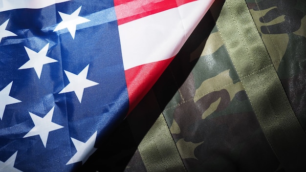 Foto bandera americana y sombrero o bolso militar. ángulo de visión superior. sombrero de soldado o casco con bandera nacional americana sobre fondo negro. represente el concepto militar con un objeto de camuflaje y la bandera de la nación de ee. uu.