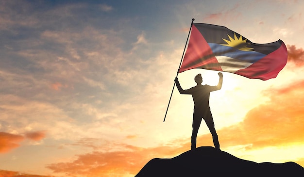 Bandera de Antigua ondeada por un hombre que celebra el éxito en la cima de una montaña 3D Rendering