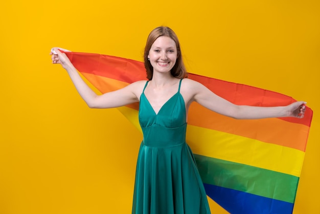 Bandera del arco iris en manos de una mujer joven Paz mundial En un estudio amarillo