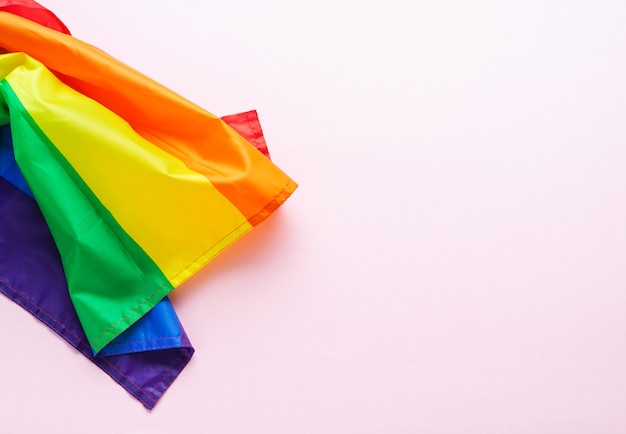 Bandera del arco iris en superficie rosa. Cultura LGBTQIA. Día del Orgullo Gay. Copie el espacio.