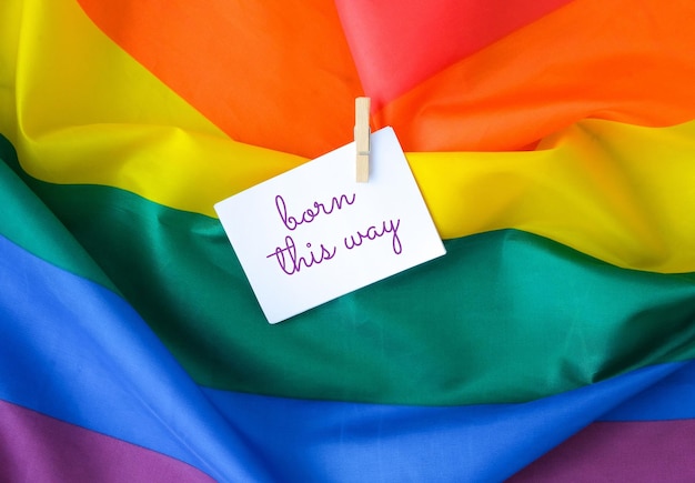 Foto bandera del arco iris con texto nacida de esta manera mensaje en una nota de papel bandera del arco iris lgbtq hecha de seda