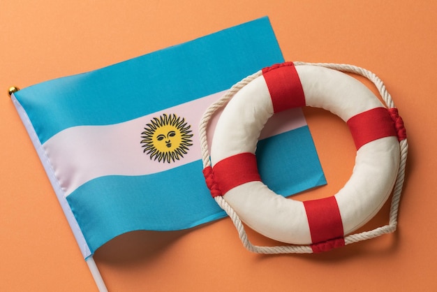 Bandera de Argentina y boya salvavidas en un concepto de fondo coloreado sobre el tema de la ayuda