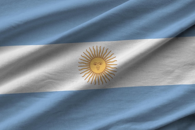 Bandera argentina con grandes pliegues ondeando de cerca bajo la luz del estudio en el interior Los símbolos y colores oficiales en la pancarta