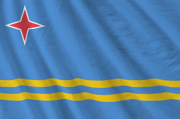 Bandera de Aruba con grandes pliegues ondeando de cerca bajo la luz del estudio en el interior Los símbolos y colores oficiales en la pancarta