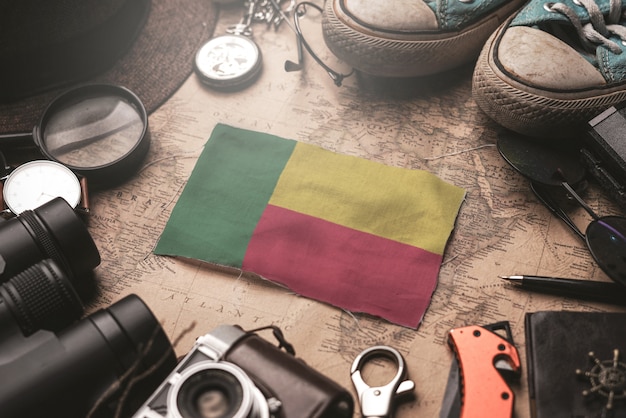 Bandera de Benin entre los accesorios del viajero en el viejo mapa vintage. Concepto de destino turístico.