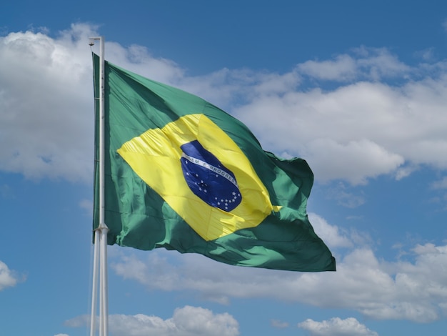 Bandera de Brasil ondeando en el cielo azul con nubes Orden y progreso en portugués brasileño