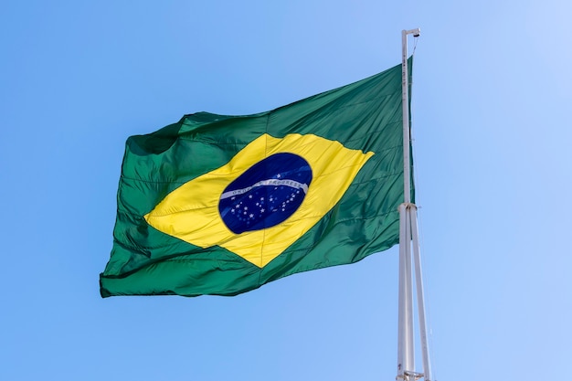 Bandera de Brasil ondeando en el cielo azul. Orden y progreso en portugués.