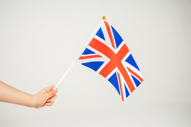 Bandera británica de la mano que agita en el fondo blanco