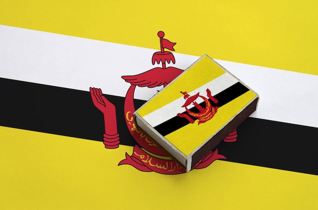 La bandera de Brunei Darussalam se representa en una caja de fósforos que se encuentra en una bandera grande