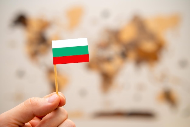 Bandera de Bulgaria en la mano del hombre en el fondo del mapa mundial