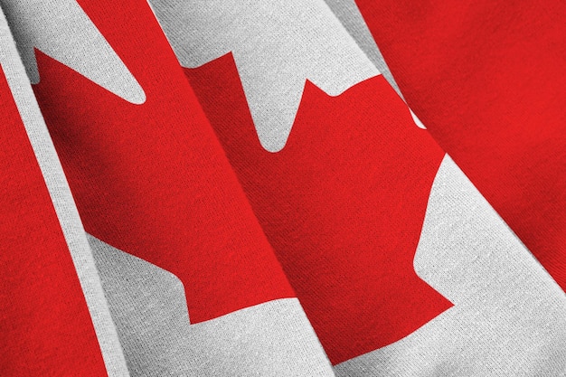 Bandera de Canadá con grandes pliegues ondeando de cerca bajo la luz del estudio en el interior Los símbolos y colores oficiales en la pancarta