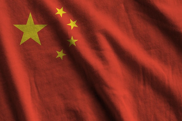 Bandera china con grandes pliegues ondeando de cerca bajo la luz del estudio en el interior Los símbolos y colores oficiales en la pancarta