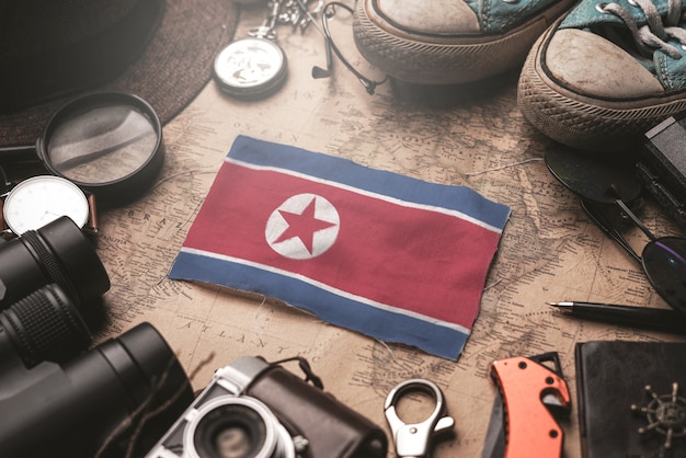 Bandera de Corea del Norte entre los accesorios del viajero en el viejo mapa vintage. Concepto de destino turístico.