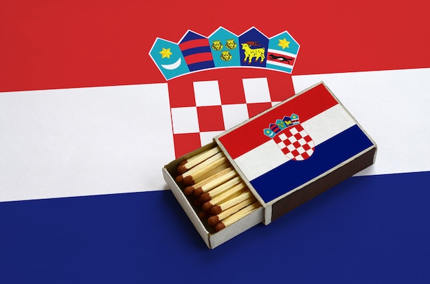 La bandera de Croacia se muestra en una caja de fósforos abierta, que está llena de fósforos y se encuentra en una bandera grande