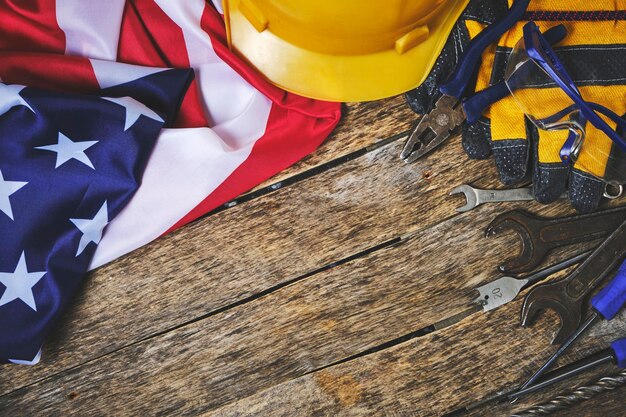 Foto bandera de ee.uu. establece herramientas de construcción y casco protector fondo de madera concepto para el día del trabajo el primero de mayo