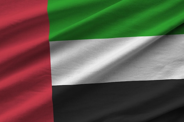 Bandera de los Emiratos Árabes Unidos con grandes pliegues ondeando de cerca bajo la luz del estudio en el interior Los símbolos y colores oficiales en la pancarta
