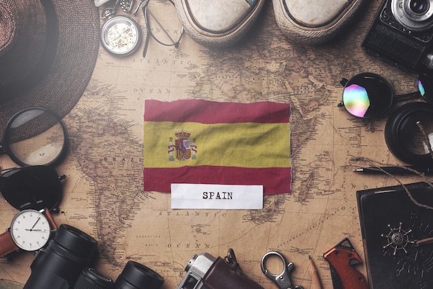 Foto bandera de españa entre los accesorios del viajero en el viejo mapa vintage. tiro de arriba