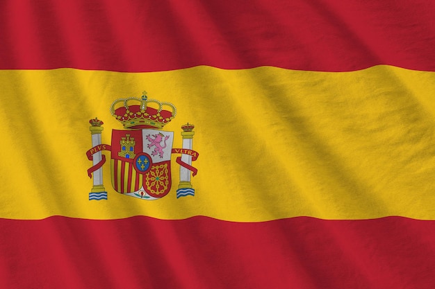 Bandera de España con grandes pliegues ondeando de cerca bajo la luz del estudio en el interior Los símbolos y colores oficiales en la pancarta