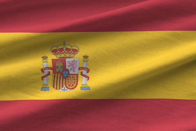 Bandera de España con grandes pliegues ondeando de cerca bajo la luz del estudio en el interior Los símbolos y colores oficiales en la pancarta