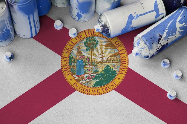 Bandera del estado de Florida y pocas latas de aerosol usadas para pintar graffiti Concepto de cultura de arte callejero