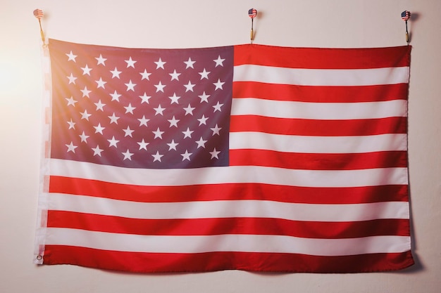 Foto bandera estados unidos américa está suspendida en una pared blanca