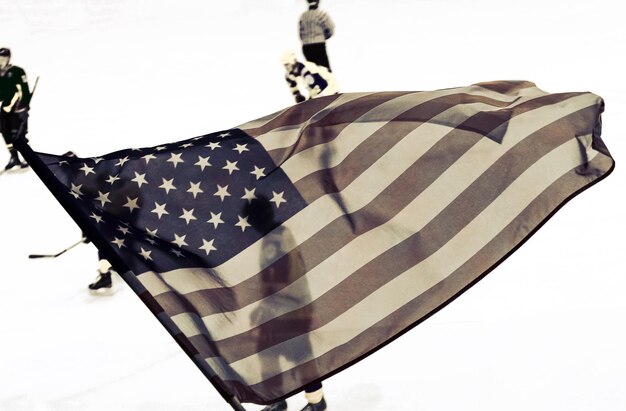 Bandera de Estados Unidos ondeando contra un fondo histórico desenfocado del juego de hockey