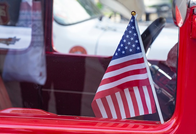 Foto bandera de estados unidos pequeña en coche rojo detrás de un cristal