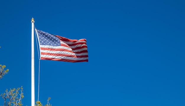 Bandera de Estados Unidos en un poste ondeando sobre fondo de cielo azul