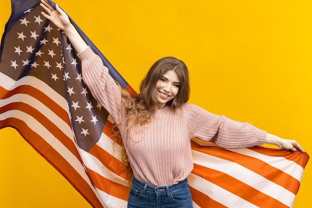 La bandera estadounidense y la belleza de la mujer se unen maravillosamente en esta foto que se destaca contra el fondo amarillo intenso y deja una impresión duradera.