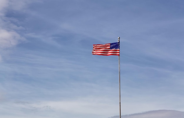 Bandera estadounidense en el cielo azul nublado