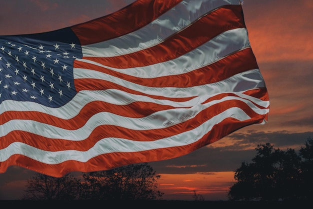 Bandera estadounidense frente al cielo brillante puesta de sol amanecer con nubes en el cielo nubes de amanecer