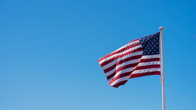 Bandera estadounidense levantada contra cielos azules claros