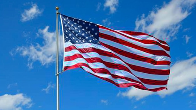Bandera estadounidense volando en el viento con nubes en el fondo