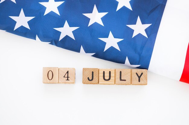 Bandera estadounidense con volantes y calendario de cubos de madera con fecha del 4 de julio Feliz Día de la Independencia