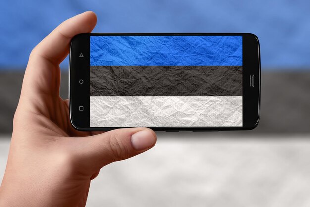 Bandera de Estonia en la pantalla del teléfono Smartphone en la mano fotografiando la bandera