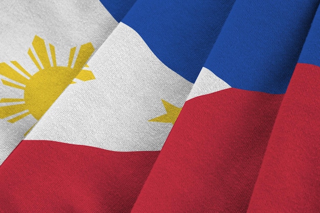 Bandera de Filipinas con grandes pliegues ondeando de cerca bajo la luz del estudio en el interior de los símbolos oficiales