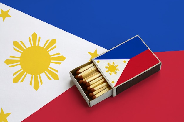 La bandera de Filipinas se muestra en una caja de fósforos abierta, que está llena de fósforos y se encuentra en una bandera grande