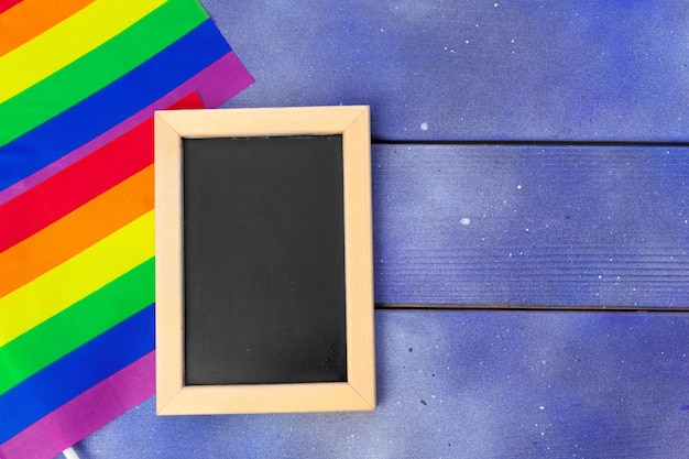Bandera gay de arco iris brillante sobre fondo de madera y espacio en blanco