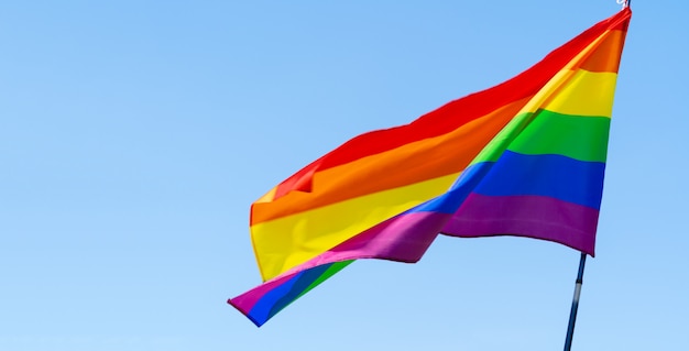 Bandera gay del arco iris ondeando en el viento en un cielo azul claro