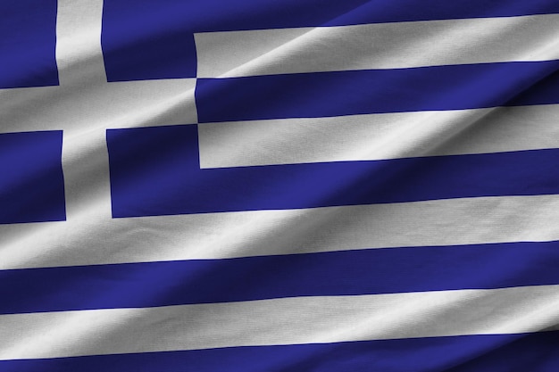 Bandera de Grecia con grandes pliegues ondeando de cerca bajo la luz del estudio en el interior Los símbolos y colores oficiales en la pancarta