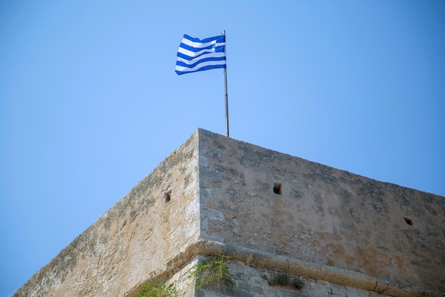 Bandera griega ondeando en la fortaleza veneciana de Koules en el antiguo puerto de Heraklion Destino de la isla de Creta Grecia