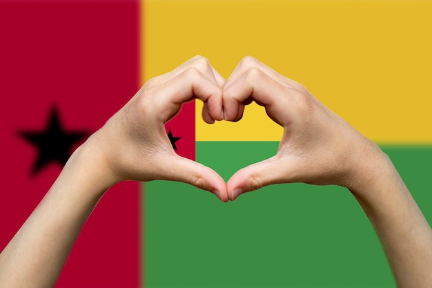 Foto bandera de guinea-bissau con dos manos en forma de corazón mano corazón símbolo de amor apoyo o donar a guinea