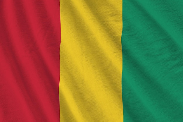 Bandera de Guinea con grandes pliegues ondeando de cerca bajo la luz del estudio en el interior Los símbolos y colores oficiales en la pancarta