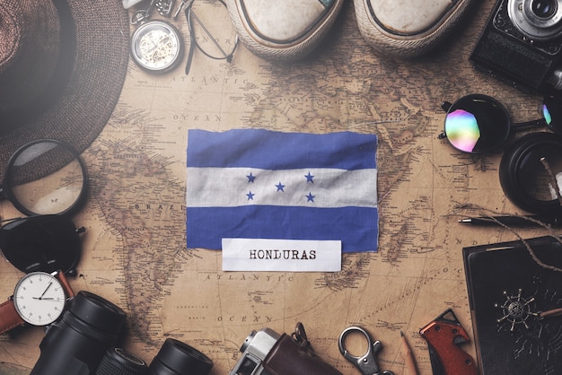 Bandera de Honduras entre los accesorios del viajero en el viejo mapa vintage. Tiro de arriba