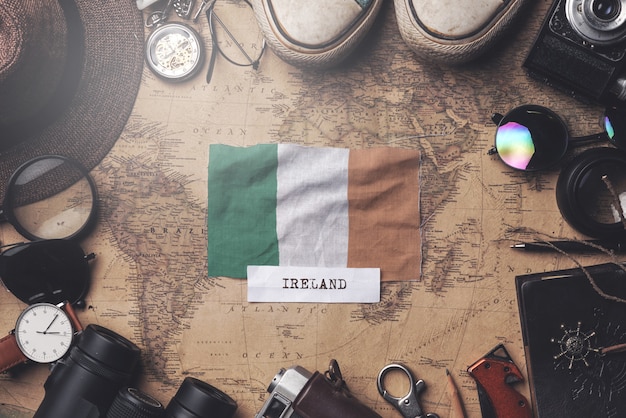 Bandera de Irlanda entre los accesorios del viajero en el viejo mapa vintage. Tiro de arriba