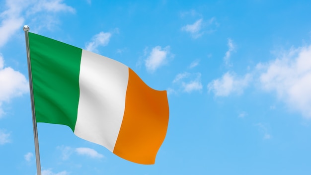 Bandera de Irlanda en la pole. Cielo azul. Bandera nacional de irlanda