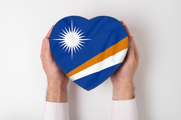 Bandera de la Isla Marshall una caja en forma de corazón en manos masculinas. blanco