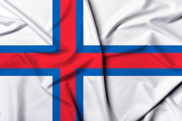 La bandera de las Islas Feroe, bellamente ondeada y a rayas, tiene una textura de fondo de colores vibrantes.