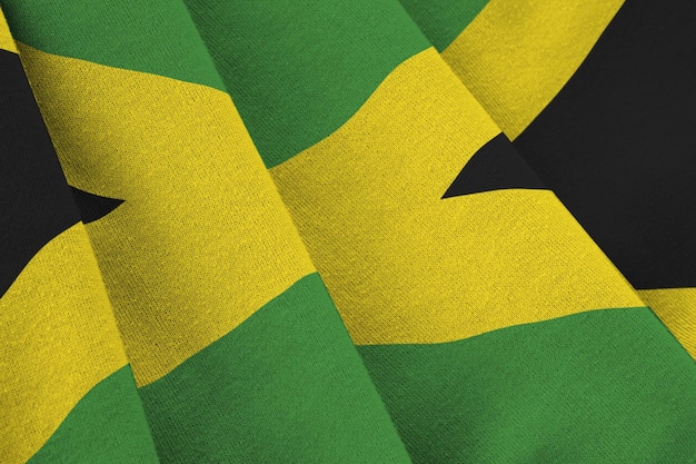 Bandera de Jamaica con grandes pliegues ondeando de cerca bajo la luz del estudio en el interior Los símbolos y colores oficiales en la pancarta